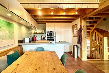 A kitchen with a table and chairs and a trash can