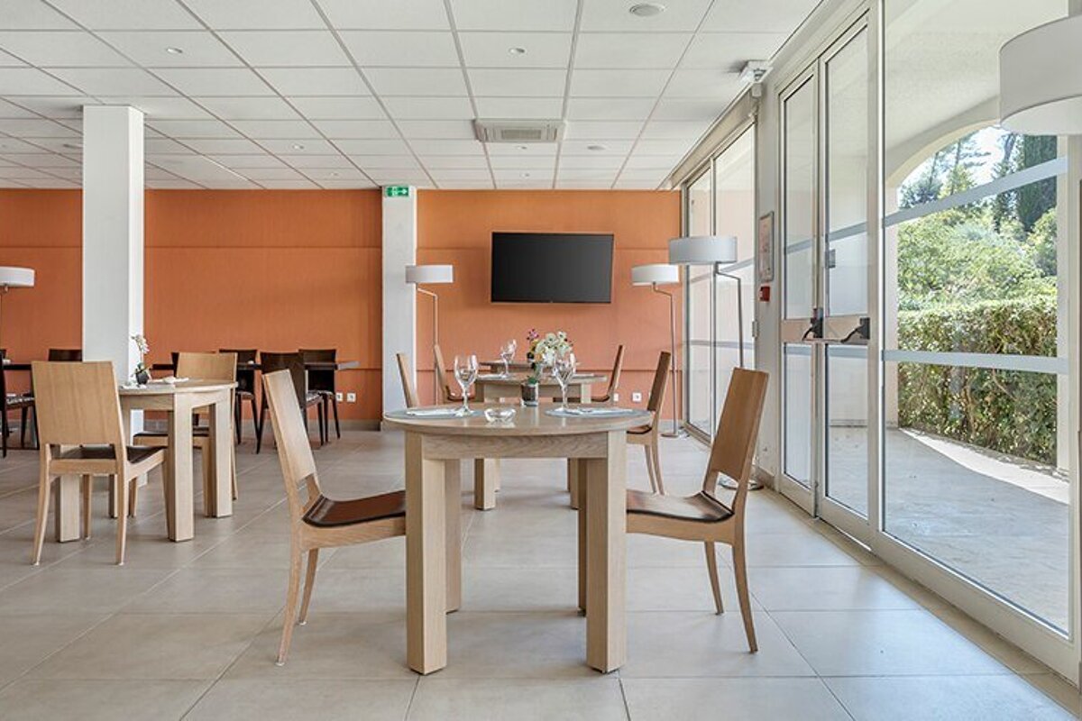 A dining room with tables and chairs and a flat screen tv
