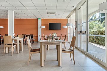 A dining room with tables and chairs and a flat screen tv