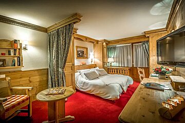 A hotel room with a bed a desk and a television