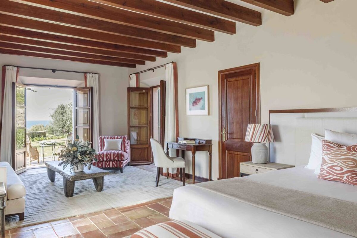 A bedroom with two beds and a table with a vase of flowers on it