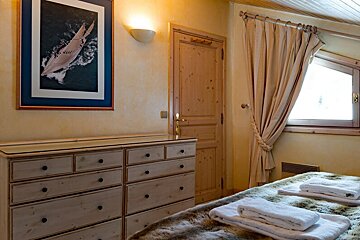 A bedroom with a dresser and a picture of a sailboat on the wall