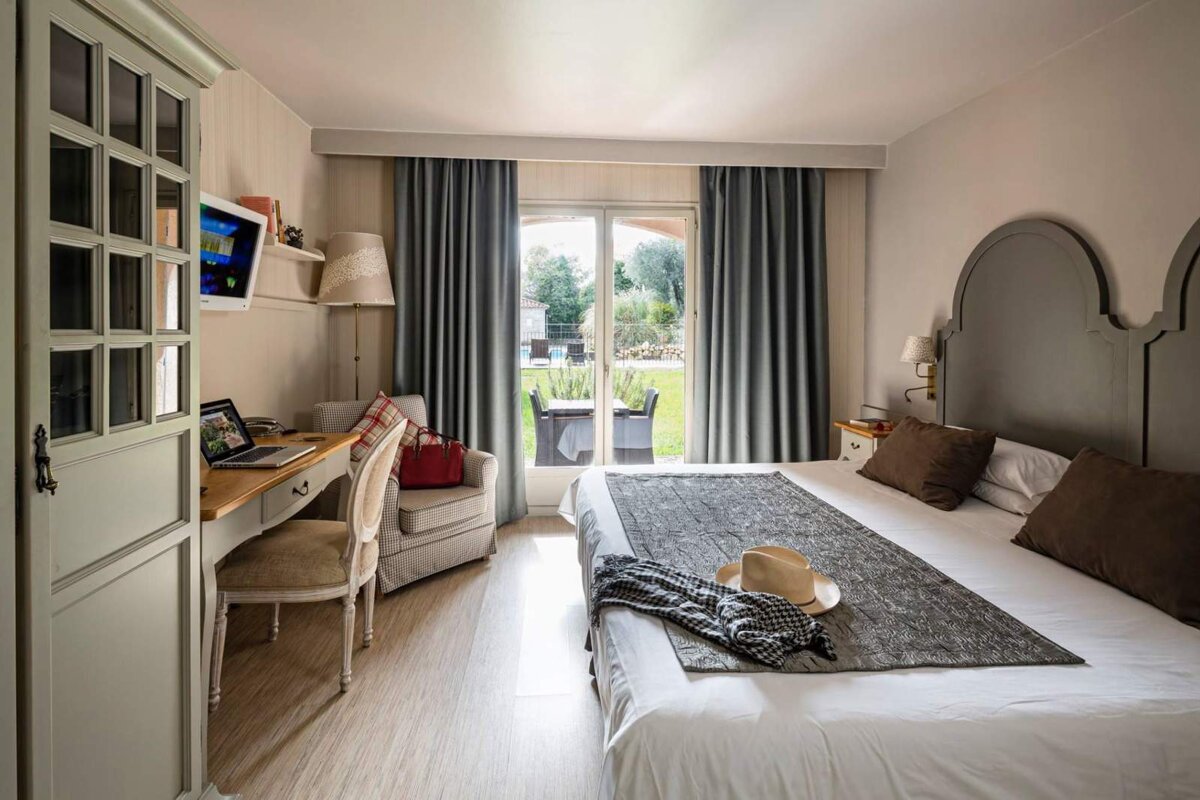 A bedroom with a large bed and a desk with a laptop on it