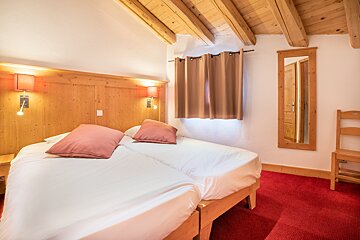 A bedroom with two beds a chair and a mirror