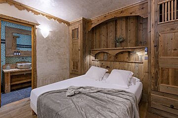 A bedroom with a wooden wall and a bed