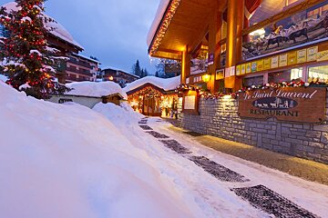 A snowy street with a sign that says le saint laurent restaurant