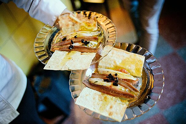Two plates of food with anchovies and bread on them