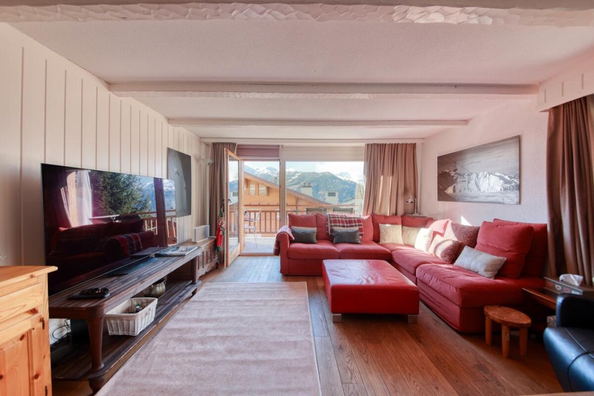 A living room with a red sectional couch and a flat screen tv