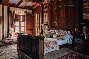A bedroom with a four poster bed and striped walls