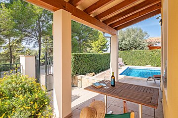 A bottle of wine sits on a table in front of a pool