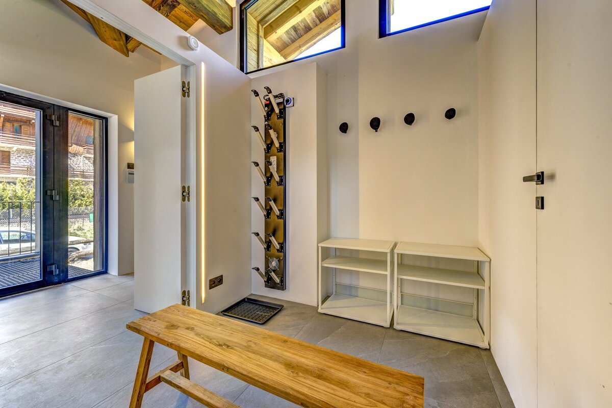 A wooden bench sits in a hallway next to a shoe rack