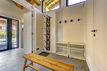 A wooden bench sits in a hallway next to a shoe rack
