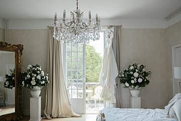 A bedroom with two vases of flowers and a chandelier