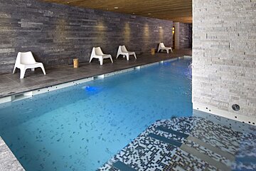 A large indoor swimming pool with chairs around it