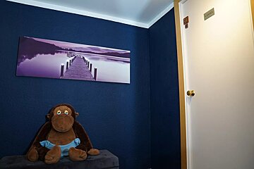 A stuffed monkey sits in front of a door that has a sign on it that says xxx