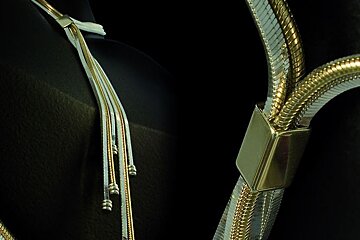 A close up of a gold and silver necklace on a black background