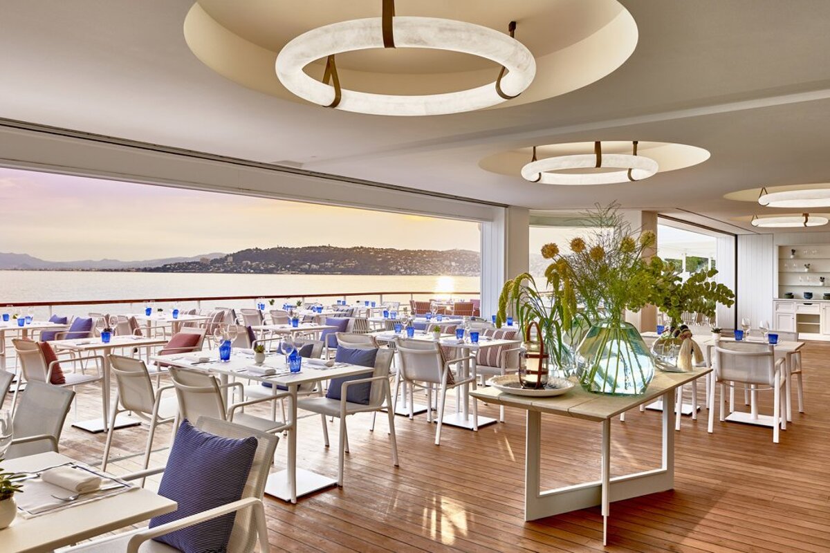 A restaurant with tables and chairs with a view of the ocean