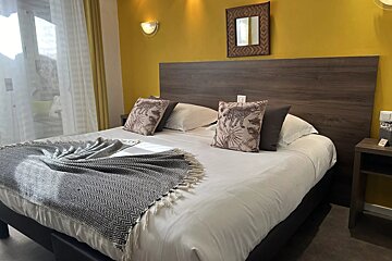 A bed with a blanket and pillows in a hotel room