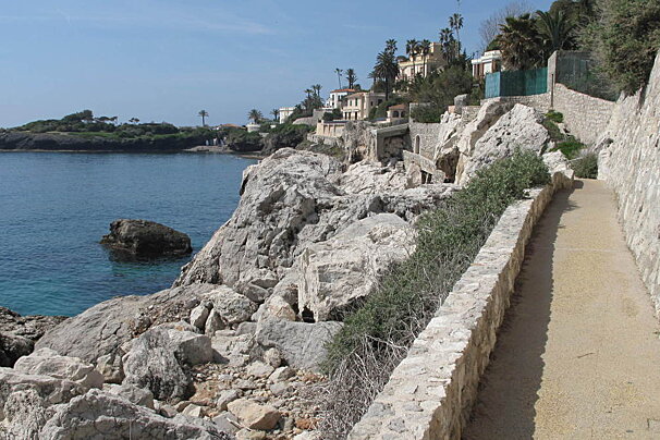 A stone walkway leads to a cliff overlooking the ocean