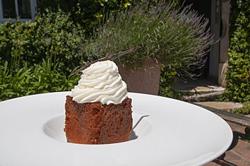 A piece of cake with whipped cream on top on a white plate