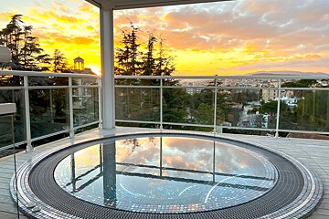 A hot tub on a balcony overlooking a city at sunset