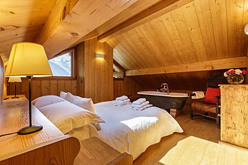 A bedroom with a large bed and a bathtub