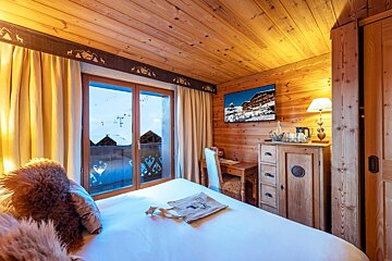 A wooden room with a bed and a desk