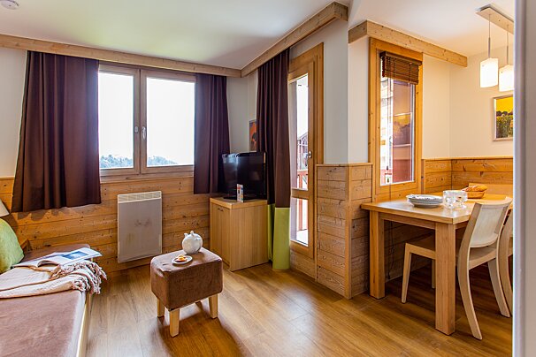 A living room with a table and chairs and a television