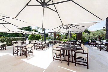 A restaurant with tables and chairs under umbrellas