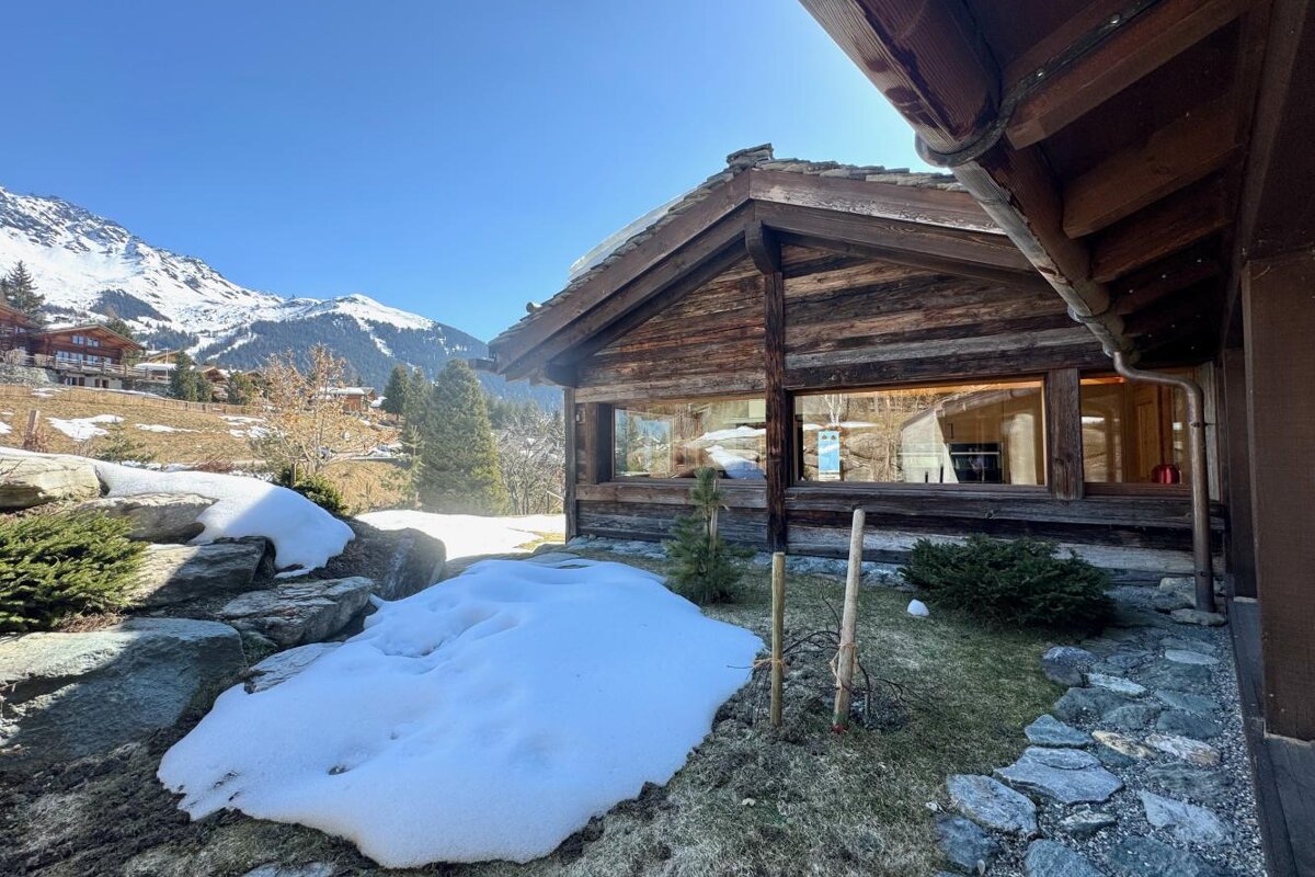 A wooden house with snow on the ground in front of it