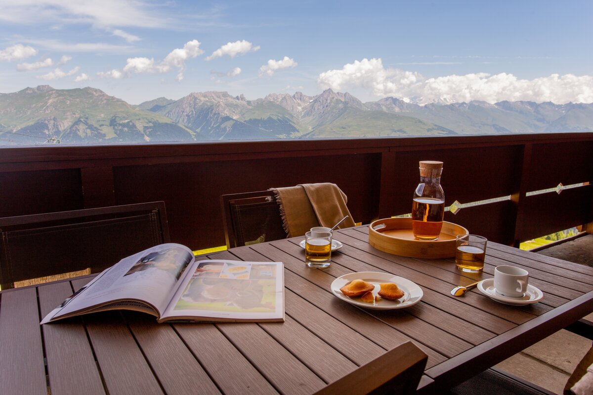 A book is open on a table with a view of mountains in the background
