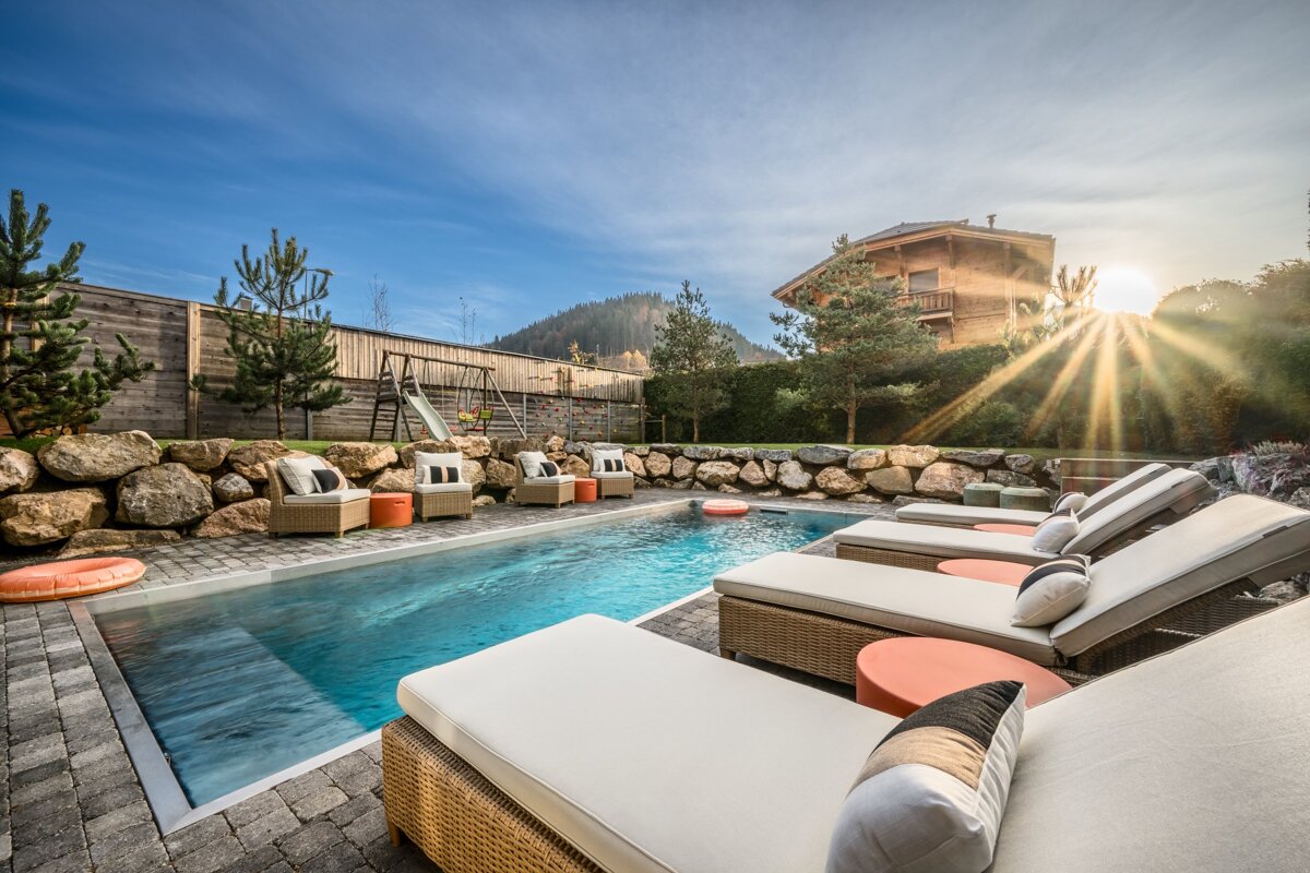 A swimming pool surrounded by lounge chairs and a slide