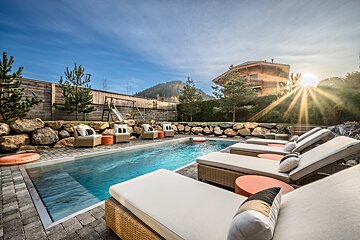 A swimming pool surrounded by lounge chairs and a slide