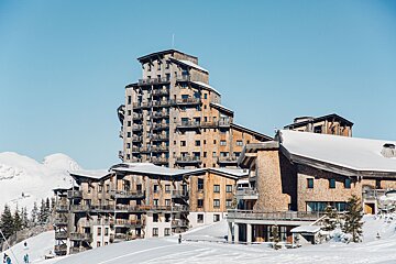 A large building with a lot of balconies is covered in snow