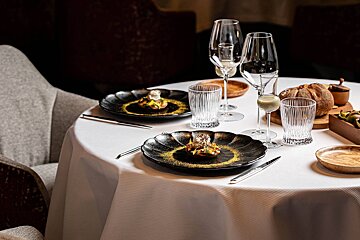 A table with plates of food and wine glasses on it