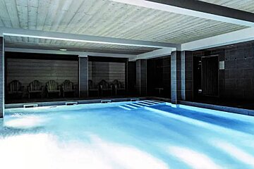 A large indoor swimming pool with chairs around it