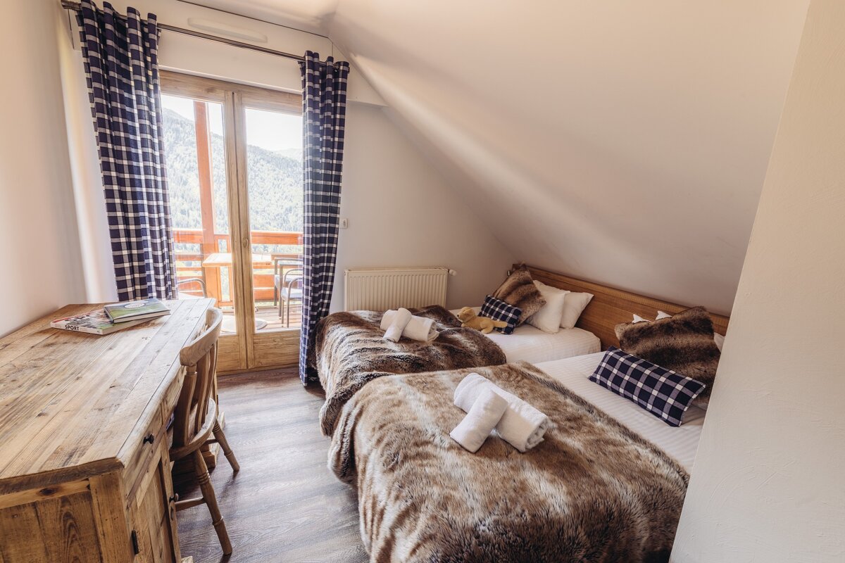 A bedroom with two beds and a wooden desk