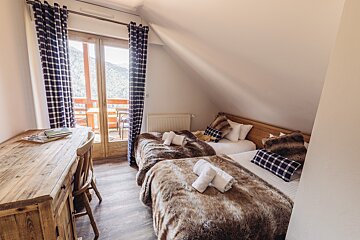 A bedroom with two beds and a wooden desk
