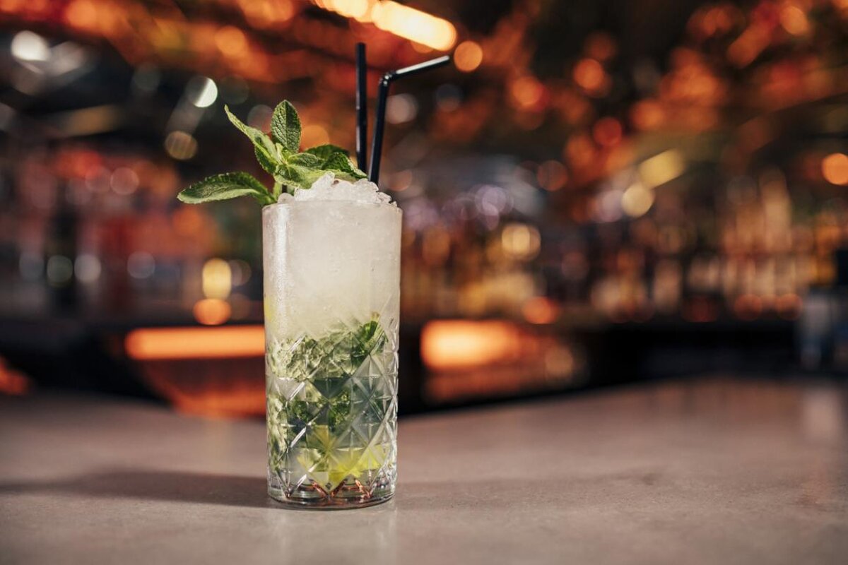 A drink in a tall glass with ice and mint leaves
