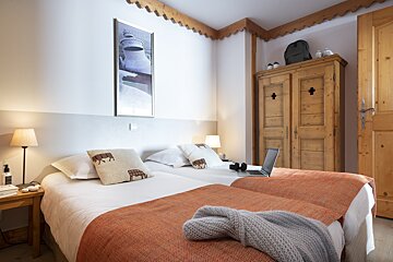 A bedroom with two beds and a laptop on the bed