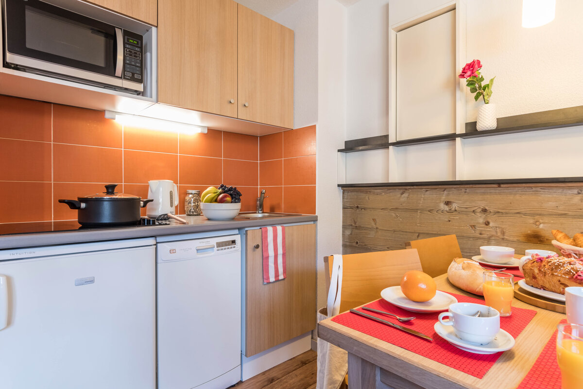 A kitchen with a microwave and a dishwasher and a table set for breakfast