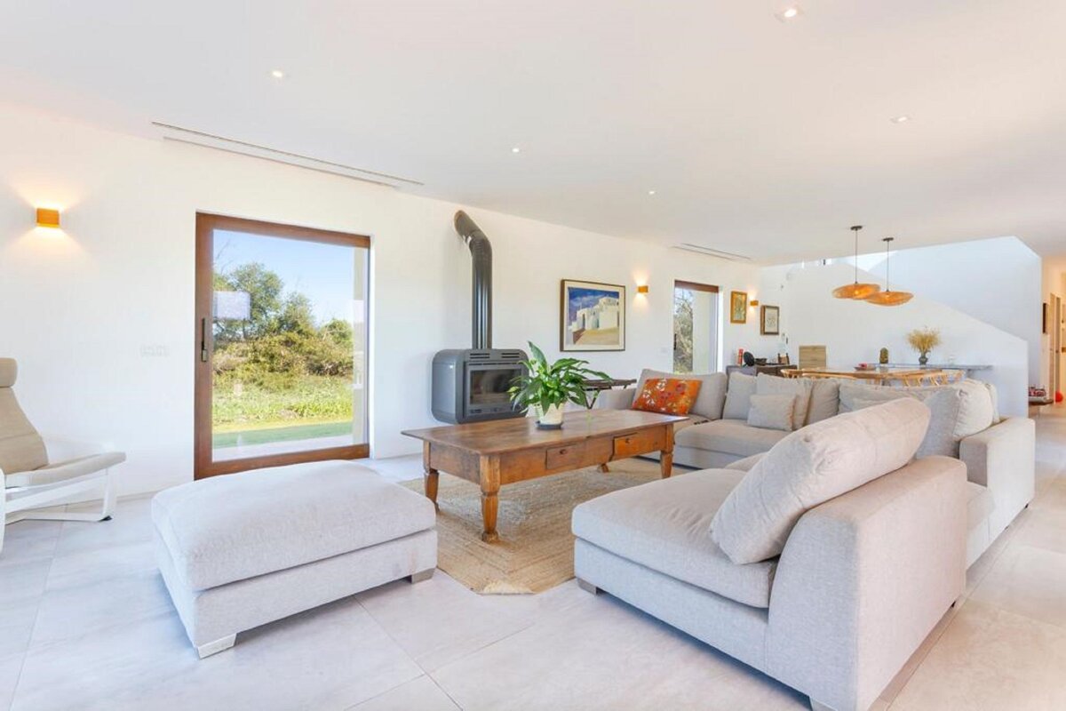 A living room with white furniture and a wood stove
