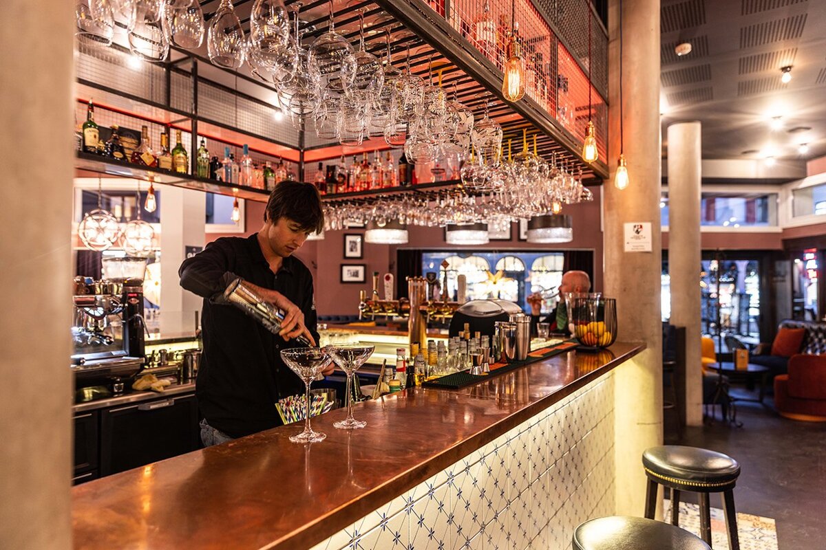 A bartender pours a drink into a martini glass