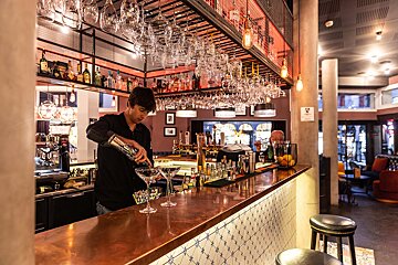 A bartender pours a drink into a martini glass
