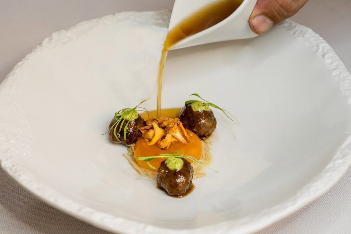 A person pouring sauce on a plate of food