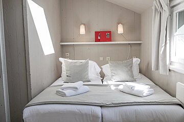 A small bedroom with two beds and a red book on the shelf