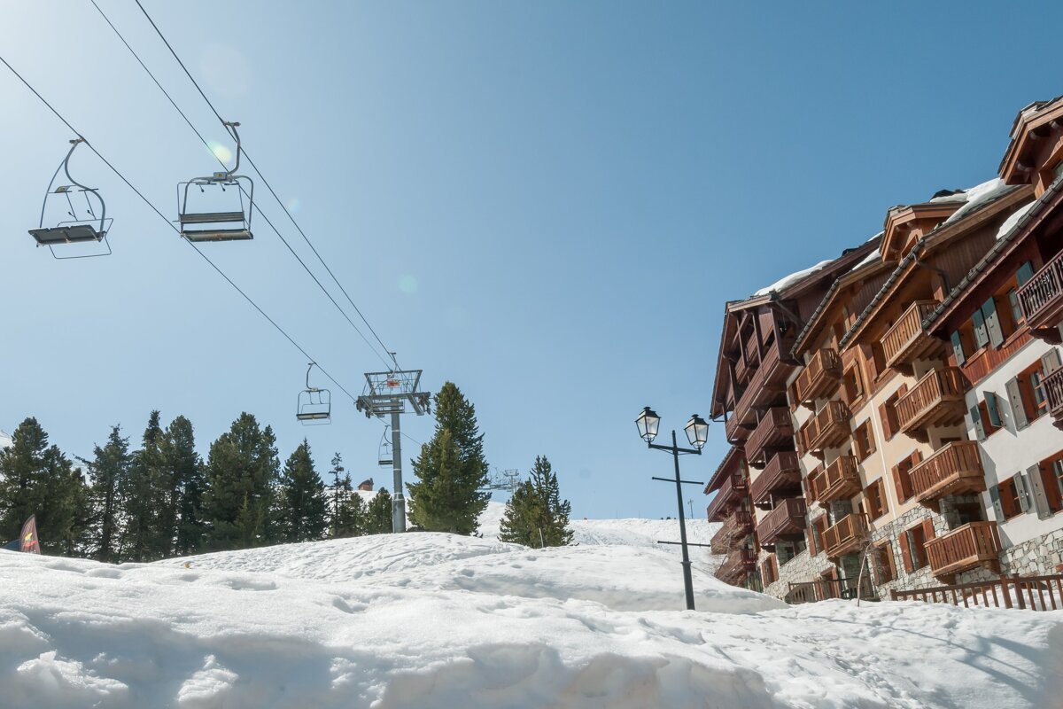 A ski lift is going up a snowy hill in front of a building