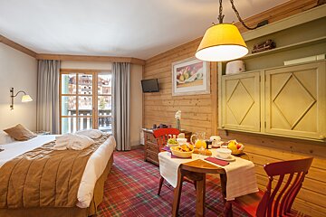 A hotel room with a bed and a table with breakfast on it