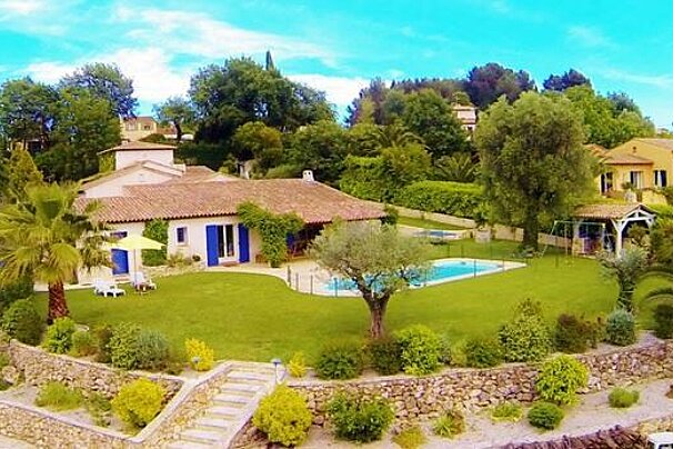 An aerial view of a large house with a swimming pool in the backyard surrounded by trees