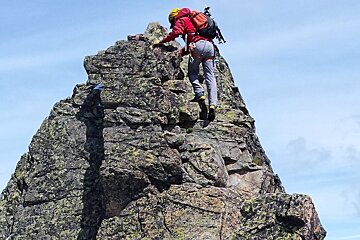 someone climbing up tot he top of a rocky peak
